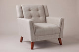 Comacchio tufted mid-century armchair in beige, three-quarter view on a warm grey studio backdrop