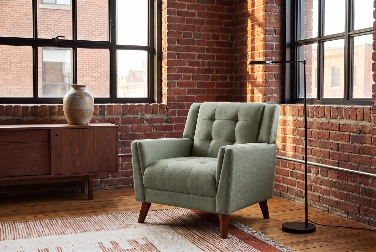Comacchio armchair in green in a brick-walled loft with steel windows, a walnut sideboard and a black floor lamp