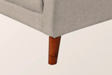 Close-up of the light brown front corner and a tapered solid wood leg in a walnut finish