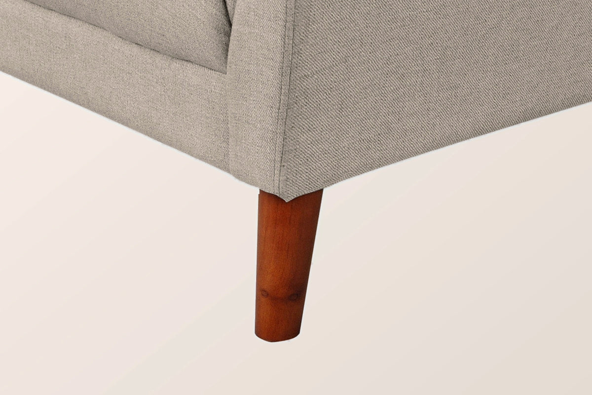 Close-up of the light brown front corner and a tapered solid wood leg in a walnut finish