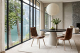 Two Compiano dining chairs in distressed brown leather at a round basalt-top table in a Bella Coola valley house