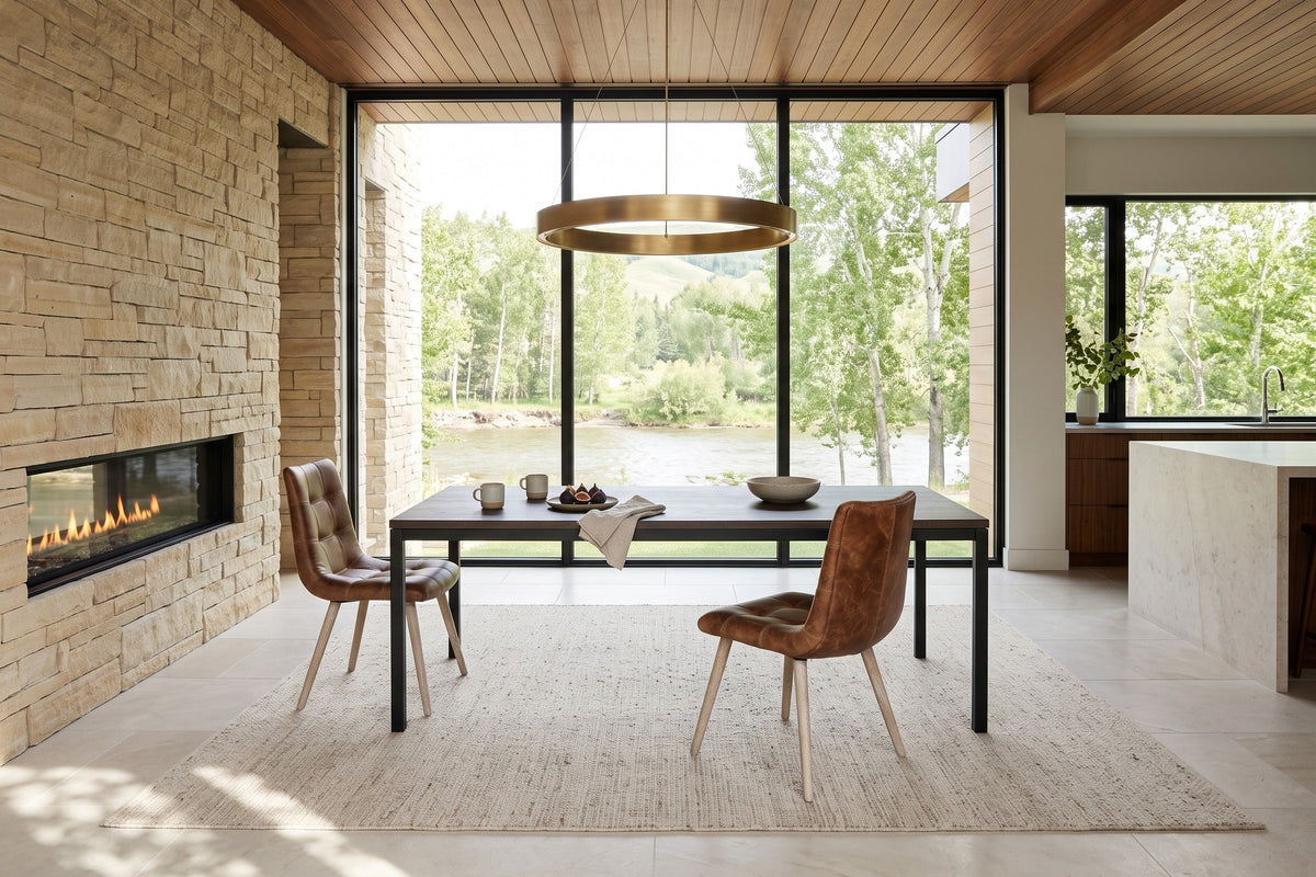 Two Compiano dining chairs in distressed brown leather at a smoked-oak table in a Calgary house on the Elbow River