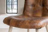Close-up of the Compiano seat in distressed brown leather: the stitched grid, twin topstitching and the thick front roll