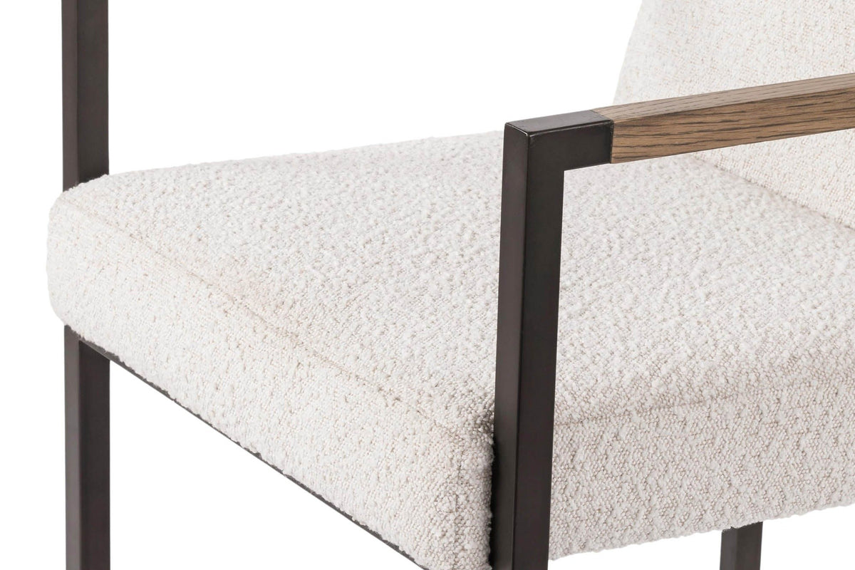 Close-up of the Coreglia arm and seat: an ash wood arm bar between metal corners, the thick seat in white looped fabric