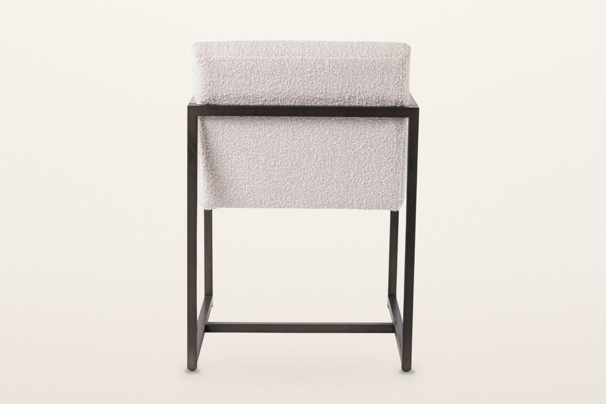 Back of the Coreglia dining armchair in White on a warm white studio backdrop: the covered back above the metal back rail