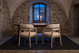 A pair of Corinaldo dining chairs at a walnut table lit by candles in a vaulted stone dining room in Quebec City
