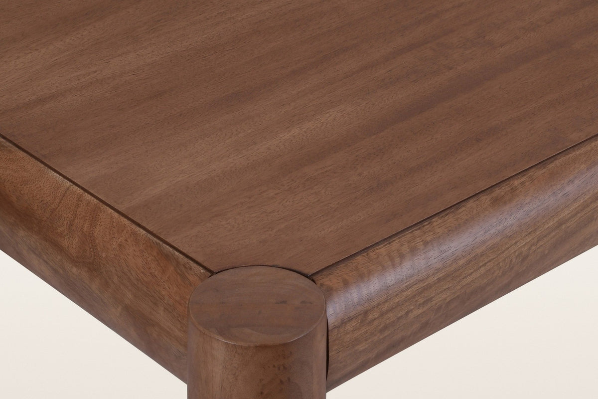 Close-up of a Corniglia top corner in walnut: the round leg top set between two rounded rails and the mango veneer panel