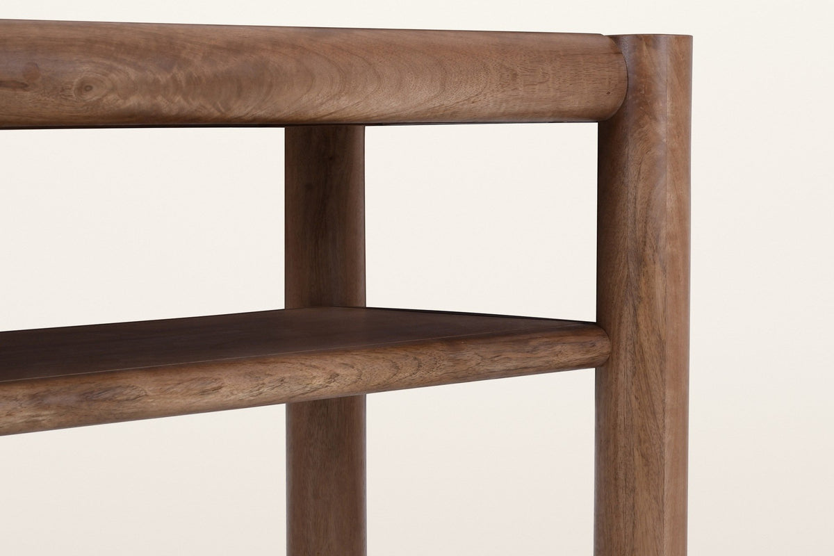 Close-up of the Corniglia console in walnut: the round top rail running into a leg, and the rounded front edge of the shelf below