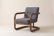 Corwin accent chair in Charcoal, three-quarter view on a warm off-white studio backdrop: a tufted seat and back inside a loop