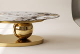 Close-up of the Cosima coffee table's base: the large polished gold sphere on the oval plinth beneath the stone top