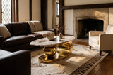 The Cosima coffee table on a cream and tobacco rug between a chocolate leather sofa and a cream armchair, beside a limestone fireplace under dark oak beams