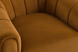 Close-up of the caramel velvet seat with its stitched front seam, the channelled back and arms around it