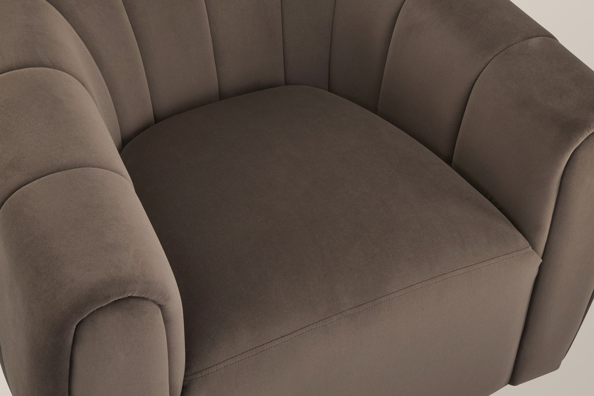 Close-up of the dark brown velvet seat with its stitched front seam, the channelled back and arms around it