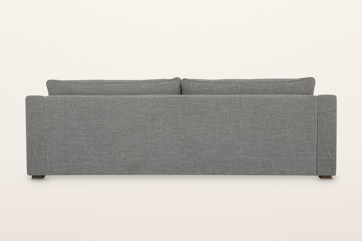 Back of the Cupramontana sofa in Grey on a warm white studio backdrop: a plain upholstered back panel with the back cushions