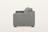 Cupramontana sofa in Grey, side view on a warm white studio backdrop: the arm top dips in a scoop and rises toward the back
