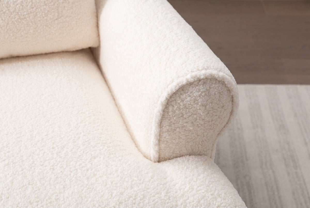 Close-up of the ivory sherpa: the round face of the rolled arm with its welt edge, beside the deep seat