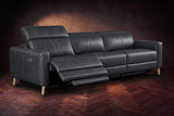 The Elodie sofa on a dark walnut herringbone floor, the left outer seat reclined with its footrest out and its headrest raised. Shown in Aged Slate, 3 seat.