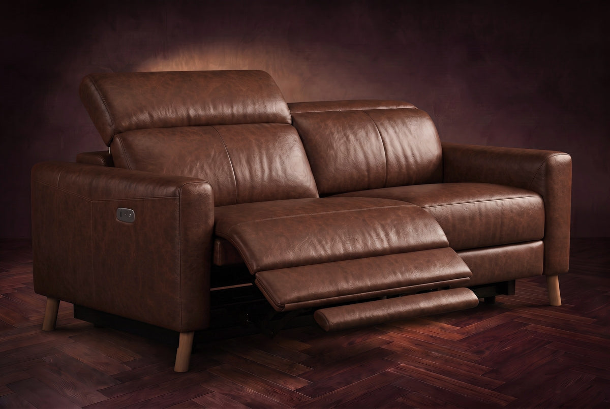 The Elodie loveseat on a dark walnut herringbone floor, the left seat reclined with its footrest out and its headrest raised. Shown in Burnished Chestnut, Loveseat.