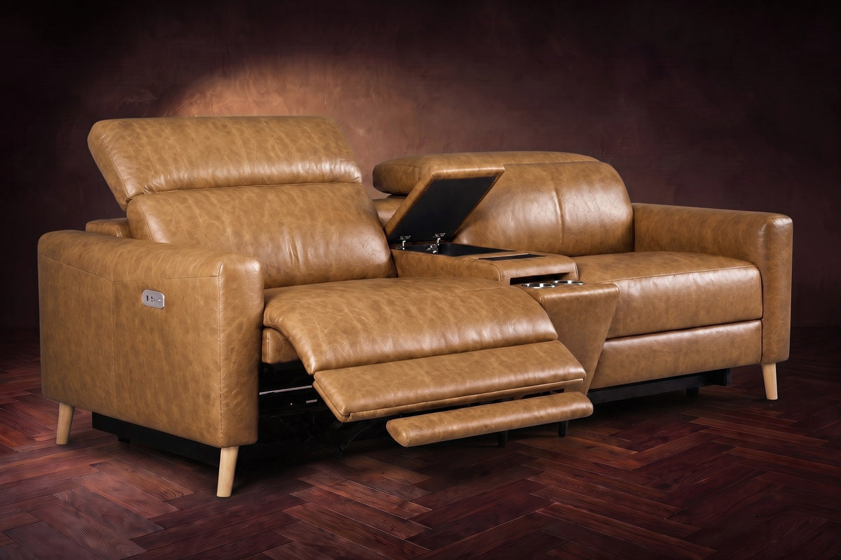 The Elodie sofa with console in Antiqued Caramel distressed full leather on a dark herringbone floor, the left seat reclined with its two-part footrest out and its headrest raised, the console lid open.