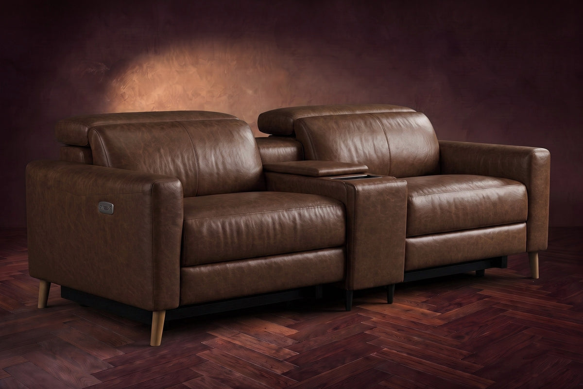 The Elodie sofa with console in Burnished Chestnut distressed full leather on a dark herringbone floor, headrests down and footrests closed.