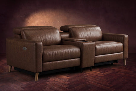 The Elodie sofa with console in Burnished Chestnut distressed full leather on a dark herringbone floor, headrests down and footrests closed.