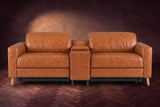 The Elodie sofa with console seen from the front in Tuscan Cognac distressed full leather on a dark herringbone floor, headrests down and footrests closed.