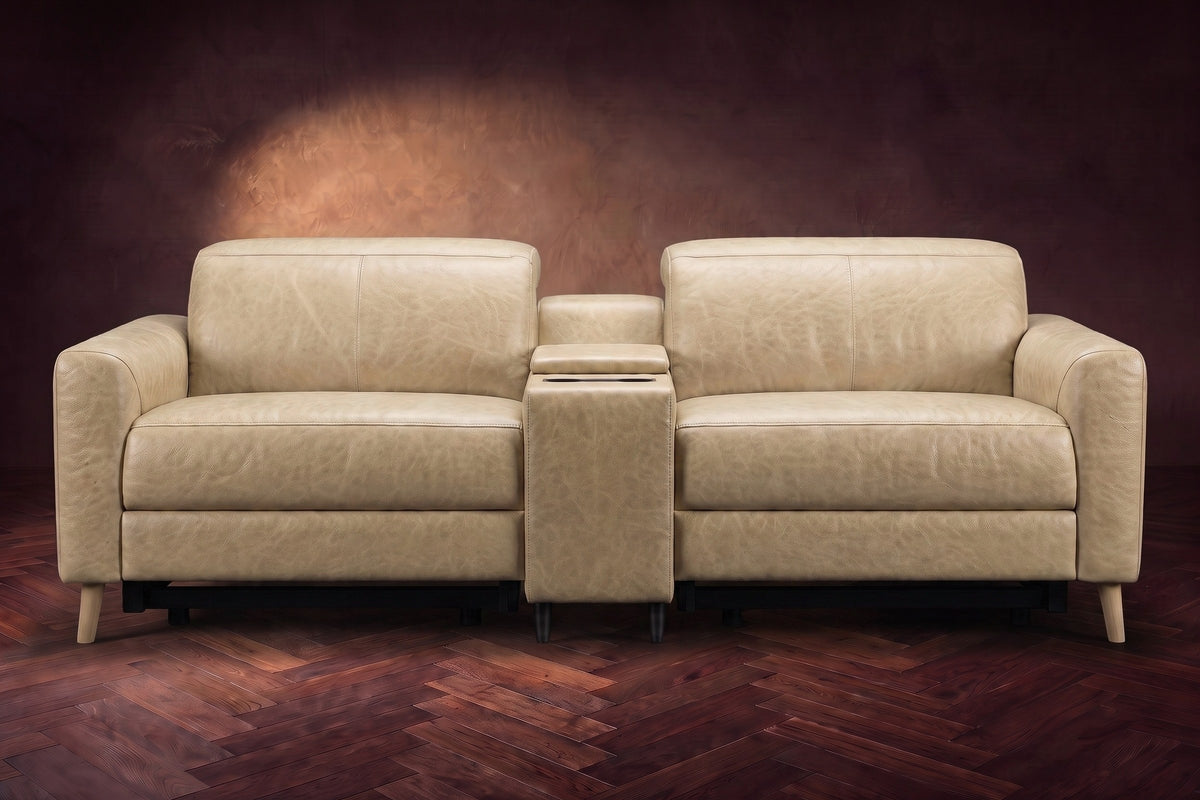 The Elodie sofa with console seen from the front in Washed Sand distressed full leather on a dark herringbone floor, headrests down and footrests closed.