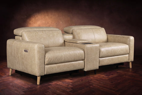 The Elodie sofa with console in Washed Sand distressed full leather on a dark herringbone floor, headrests down and footrests closed.