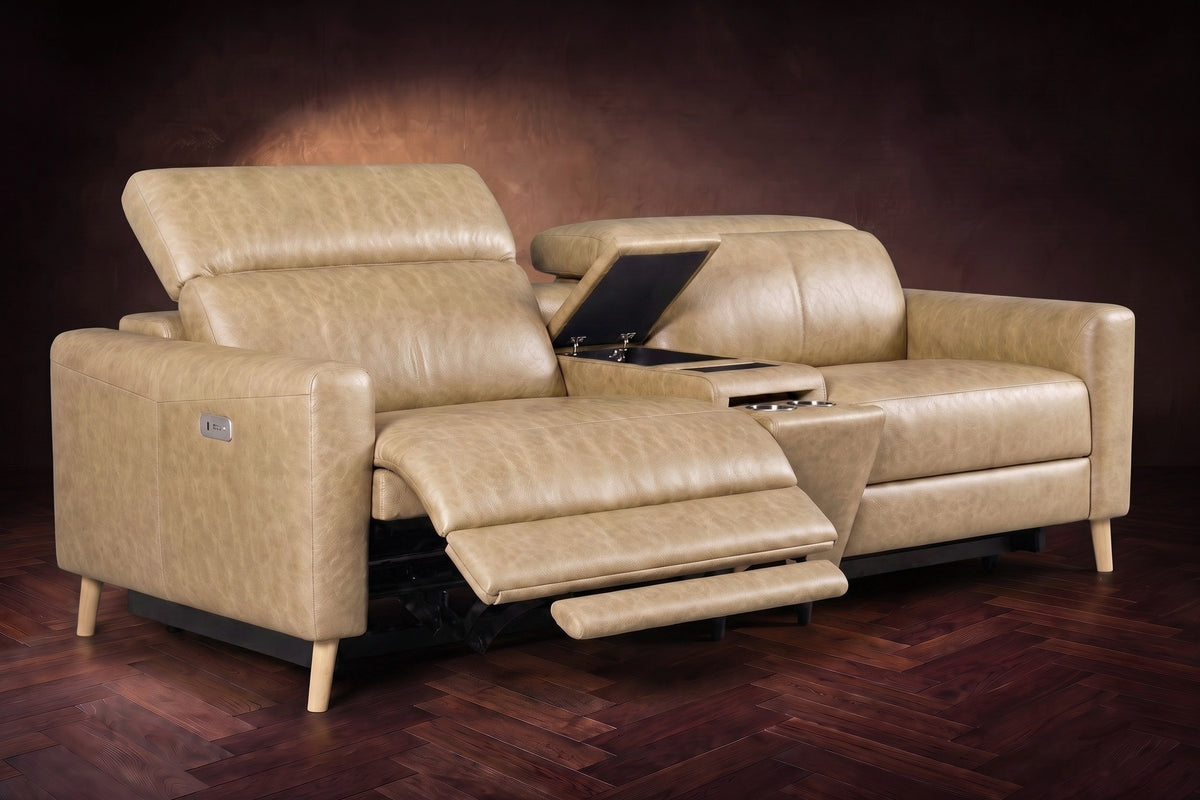 The Elodie sofa with console in Washed Sand distressed full leather on a dark herringbone floor, the left seat reclined with its two-part footrest out and its headrest raised, the console lid open.