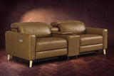 The Elodie sofa with console in Weathered Saddle distressed full leather on a dark herringbone floor, headrests down and footrests closed.