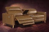 The Elodie sofa with console in Weathered Saddle distressed full leather on a dark herringbone floor, the left seat reclined with its two-part footrest out and its headrest raised, the console lid open.