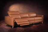 The Elodie sofa on a dark walnut herringbone floor, the left outer seat reclined with its footrest out and its headrest raised. Shown in Tuscan Cognac, 3 seat.