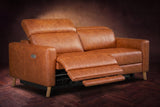The Elodie loveseat on a dark walnut herringbone floor, the left seat reclined with its footrest out and its headrest raised. Shown in Tuscan Cognac, Loveseat.