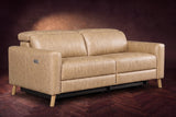 The Elodie loveseat on a dark walnut herringbone floor against a plaster wall, three-quarter view, headrests down and footrests closed. Shown in Washed Sand, Loveseat.