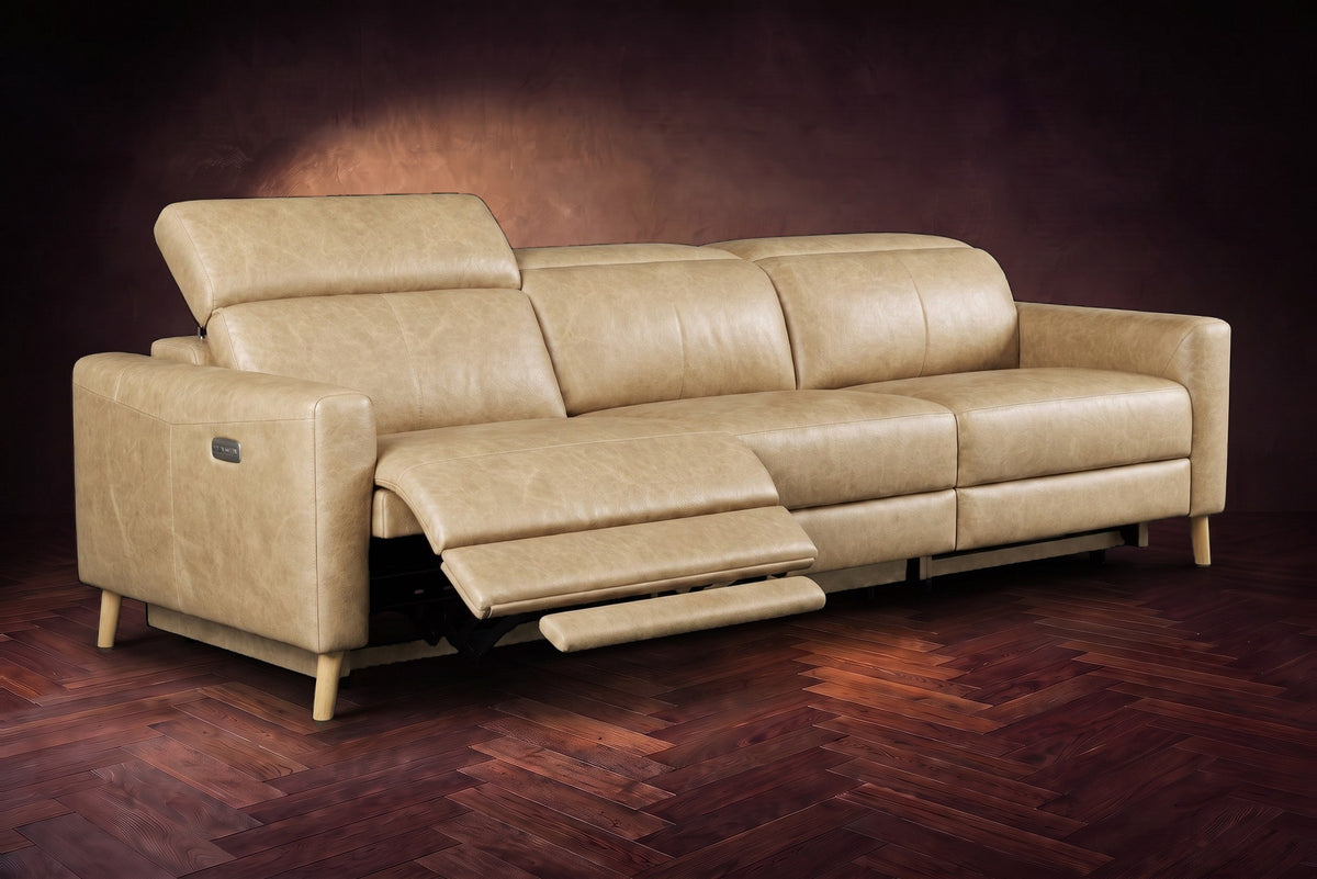 The Elodie sofa on a dark walnut herringbone floor, the left outer seat reclined with its footrest out and its headrest raised. Shown in Washed Sand, 3 seat.