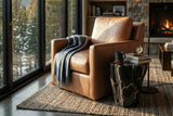 Elwood Latte leather swivel glider chair by tall windows in a cabin-style living room