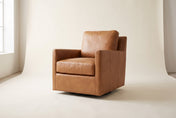 Elwood swivel glider chair in Latte leather, three-quarter view on a warm off-white studio backdrop: straight track arms