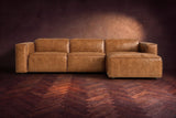 The Emery sectional in Antiqued Caramel distressed leather seen from the front on a dark walnut herringbone floor, headrests down and footrest closed. Shown in Antiqued Caramel, Right chaise.