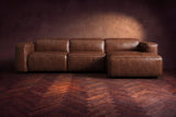 The Emery sectional in Burnished Chestnut distressed leather seen from the front on a dark walnut herringbone floor, headrests down and footrest closed. Shown in Burnished Chestnut, Right chaise.