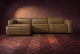 The Emery sectional in Weathered Saddle distressed leather seen from the front on a dark walnut herringbone floor, headrests down and footrest closed. Shown in Weathered Saddle, Left chaise.