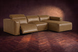 The Emery sectional in Weathered Saddle distressed leather on a dark walnut herringbone floor, the arm-end recliner open: its one-piece footrest out and its headrest raised. Shown in Weathered Saddle, Right chaise.
