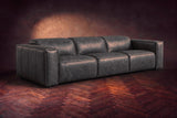 The Emery 3 seat in Aged Slate distressed full leather on a dark herringbone floor, headrests down and footrests closed. Shown in Aged Slate, 3 seat.