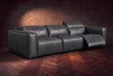 The Emery 3 seat in Aged Slate on a dark herringbone floor, the right-hand recliner open with its one-piece footrest out and its headrest raised. Shown in Aged Slate, 3 seat.