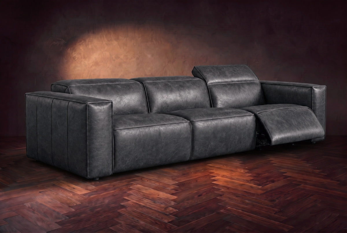 The Emery 3 seat in Aged Slate on a dark herringbone floor, the right-hand recliner open with its one-piece footrest out and its headrest raised. Shown in Aged Slate, 3 seat.