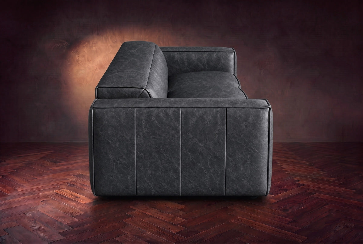 The panelled box arm of the Emery sofa seen from the side in Aged Slate, on a dark herringbone floor. Shown in Aged Slate, 3 seat.