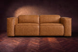 The Emery loveseat seen from the front in Antiqued Caramel distressed full leather on a dark herringbone floor, headrests down. Shown in Antiqued Caramel, Loveseat.