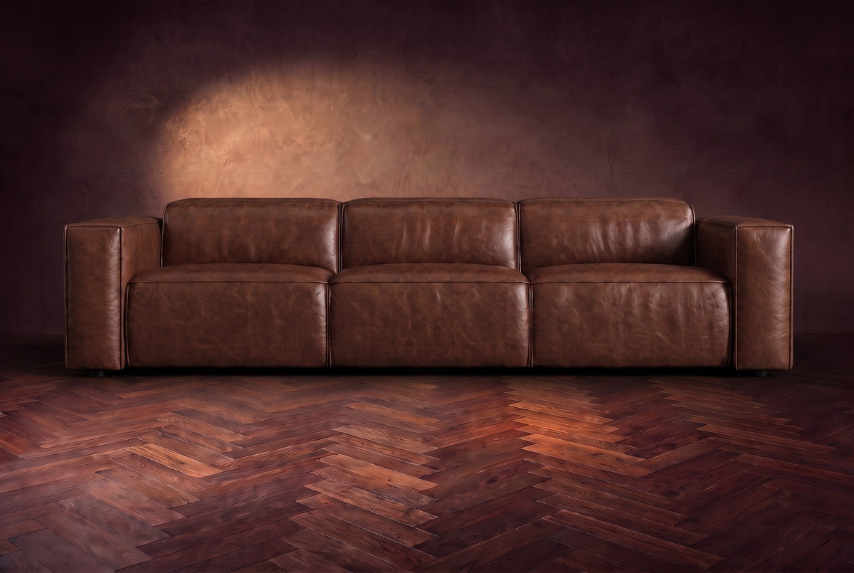 The Emery 3 seat seen from the front in Burnished Chestnut distressed full leather on a dark herringbone floor, headrests down. Shown in Burnished Chestnut, 3 seat.