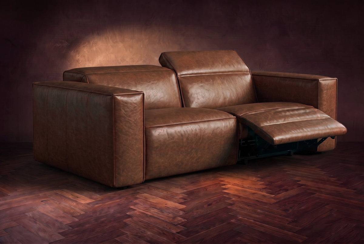 The Emery loveseat in Burnished Chestnut on a dark herringbone floor, the right-hand recliner open with its one-piece footrest out and its headrest raised. Shown in Burnished Chestnut, Loveseat.