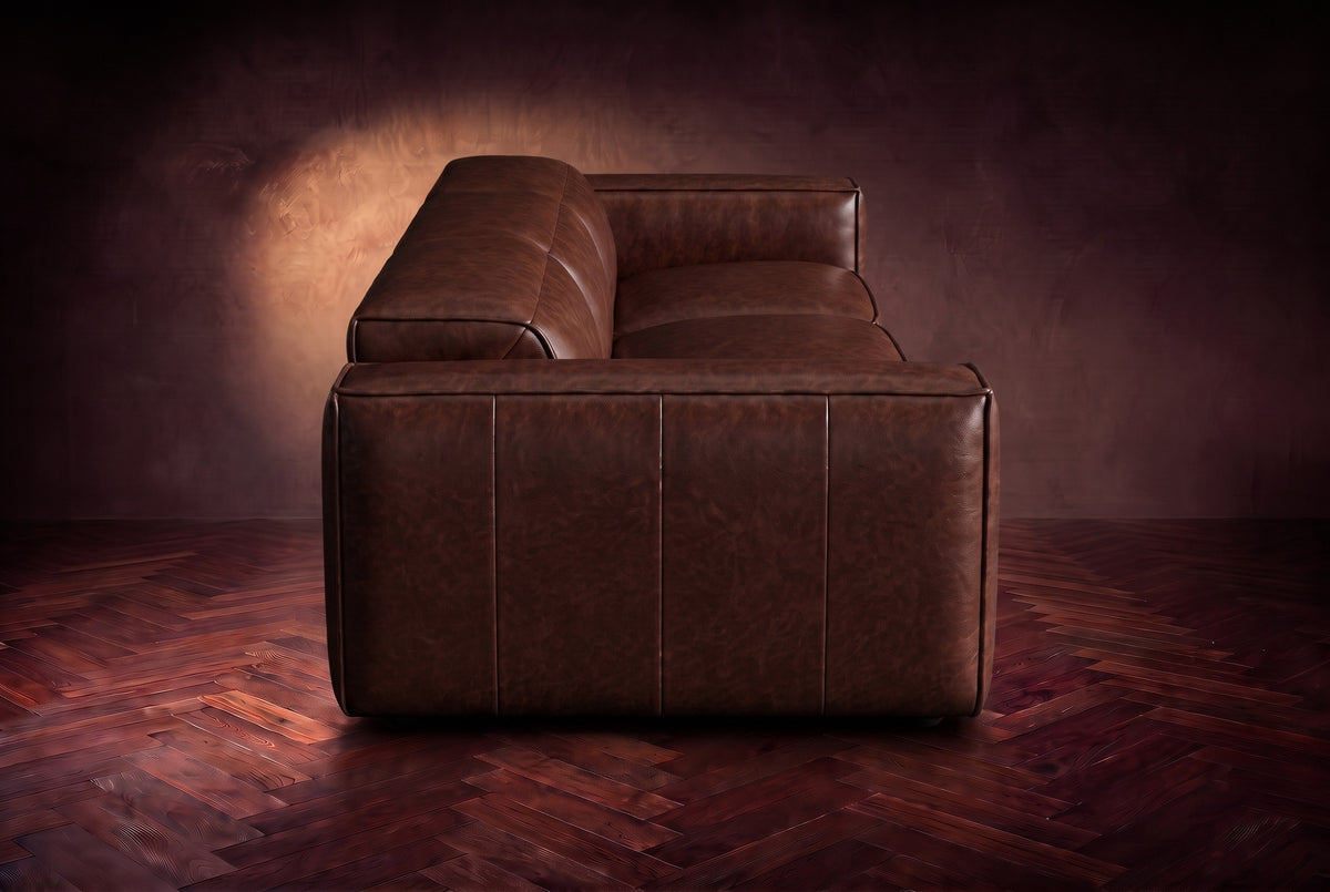 The panelled box arm of the Emery sofa seen from the side in Burnished Chestnut, on a dark herringbone floor. Shown in Burnished Chestnut, 3 seat.