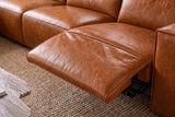 Close-up of an Emery recliner beside its box arm, the one-piece footrest out over its black steel mechanism and the closed seat beside it in line, on a woven jute rug. Shown in Tuscan Cognac.